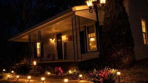 A house with a porch, a flag, and a garden with lights. - Downtown Cornelius Bungalow  Walk to Dining & Cain Center Karaoke + Darts (Cornelius)