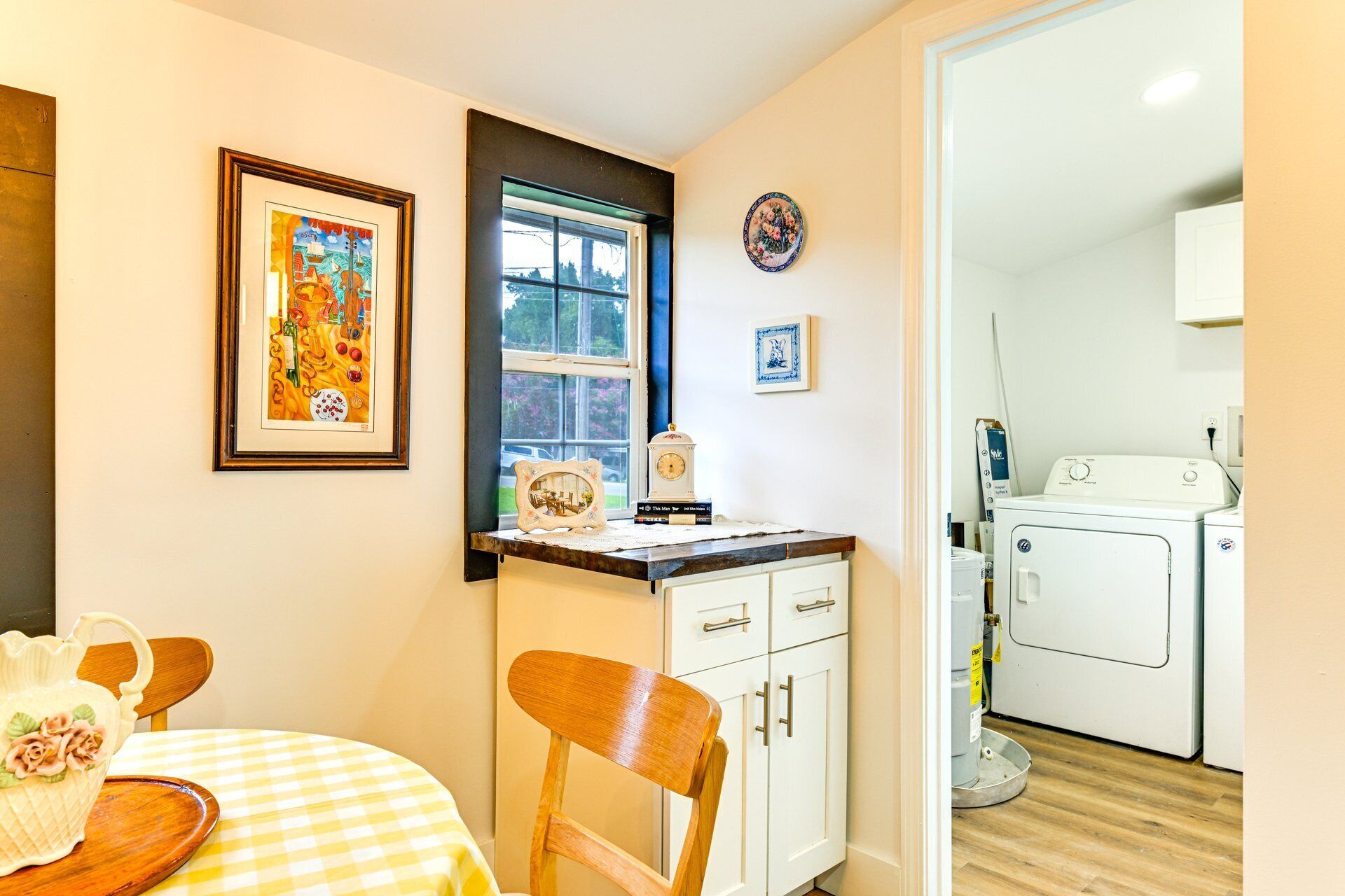 A compact kitchen with a dining area, a washing machine, and a window with a view.