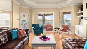 A spacious living room with a fireplace, a balcony with a stone pillar, and a view of the outdoors.