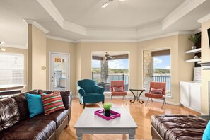 A spacious living room with a fireplace, a balcony with a stone pillar, and a view of the outdoors.