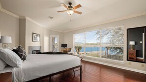 A bedroom with a bed, a ceiling fan, a desk, a chair, a TV, and a window with blinds.