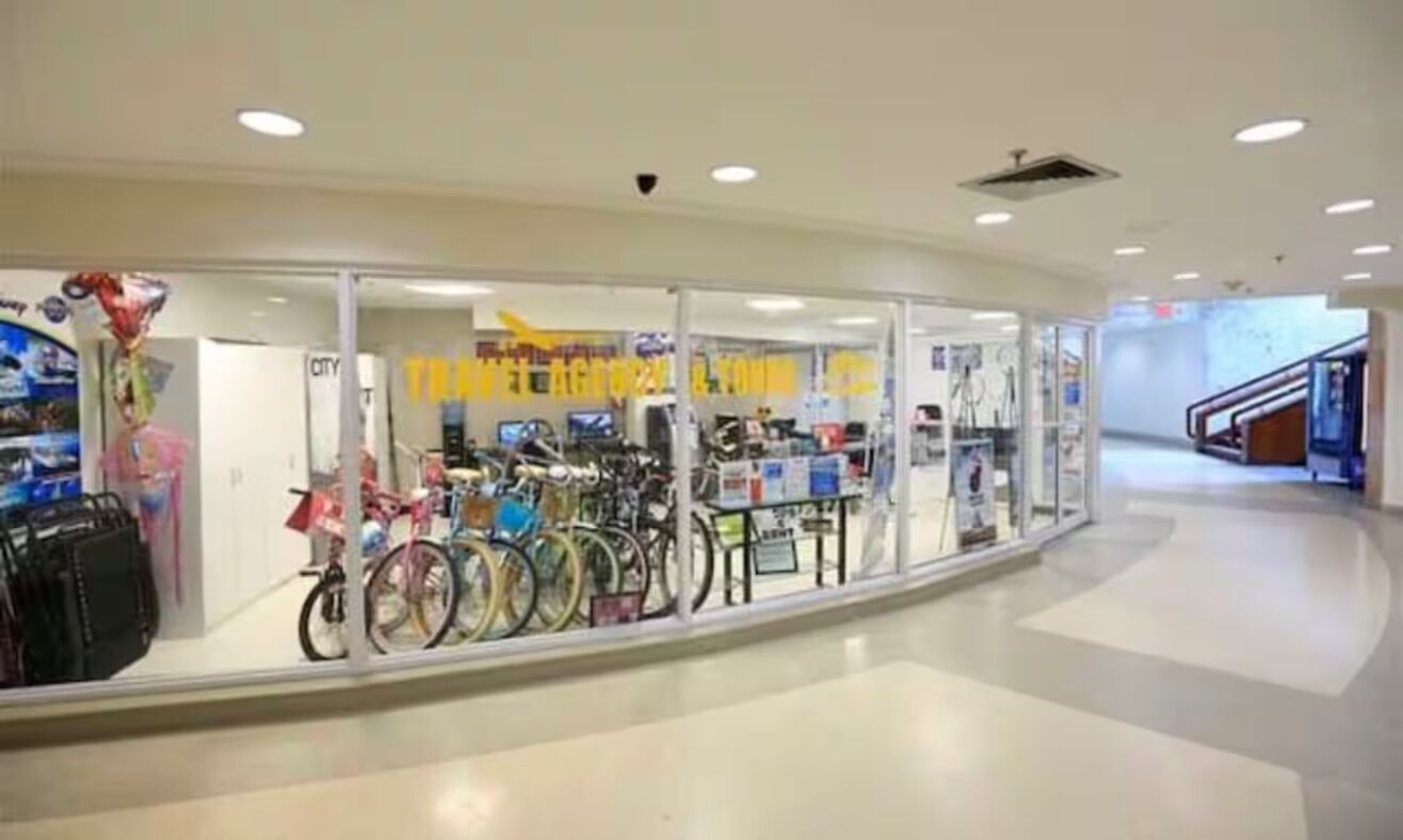 Un magasin de location de vélos avec des portes en verre, des vélos à l’intérieur et une enseigne jaune.