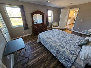 Ein Schlafzimmer mit Bett, Kommode, Stuhl und Schreibtisch.
