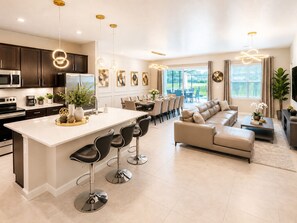 Eine moderne Küche mit einer zentralen Kochinsel, Barhocker und einem Essbereich mit einer Couch und einem Couchtisch.