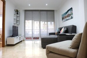 Un salon moderne avec un canapé gris, un téléviseur à écran plat et un tableau accroché au mur.