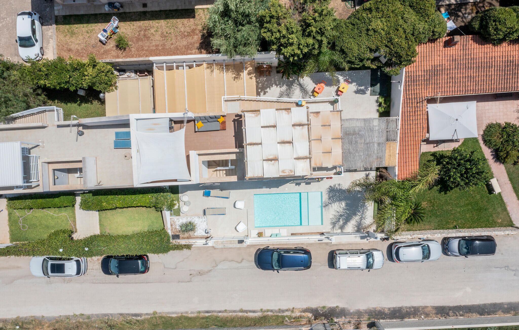 Vista aérea de un hotel moderno con piscina, varios espacios de estacionamiento y un jardín ajardinado.