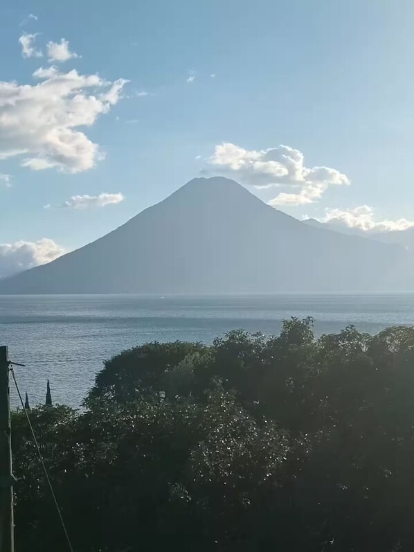 A mountain with a clear sky and calm sea in the foreground.