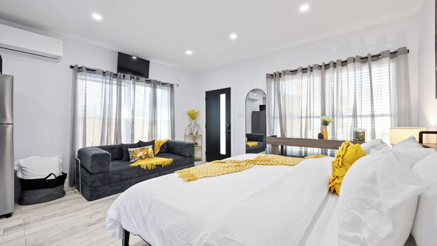 A modern hotel room with a large bed, a sofa, and a dining area. - Cityscapes Studio Suite #A @ East Downtown (Houston)