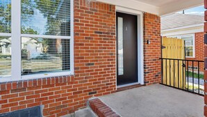 A brick house with a black door, a window with blinds, and a wooden fence. - Cityscapes Studio Suite #A @ East Downtown (Houston)