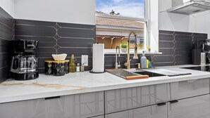 A modern kitchen with a coffee maker, wine bottles, and a sink. - Cityscapes Studio Suite #A @ East Downtown (Houston)