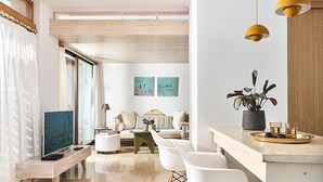 A modern living room with a TV, seating, a dining area, and artwork on the wall. - Thalassa Villas (Agios Nikolaos)