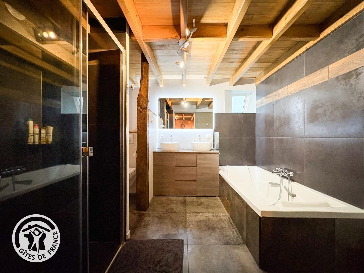 A modern bathroom with a large mirror, a white sink, and a bathtub.