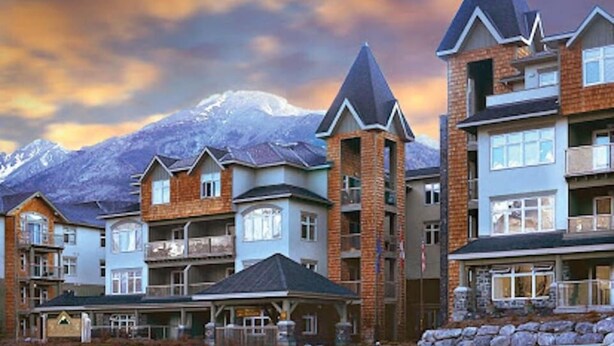 Une rangée d’immeubles à plusieurs étages, avec une chaîne de montagnes en arrière-plan.