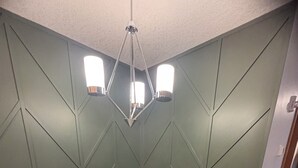 Une salle de conférence équipée d’une table ronde, de quatre chaises, d’un vase à fleurs et d’un lustre moderne.
