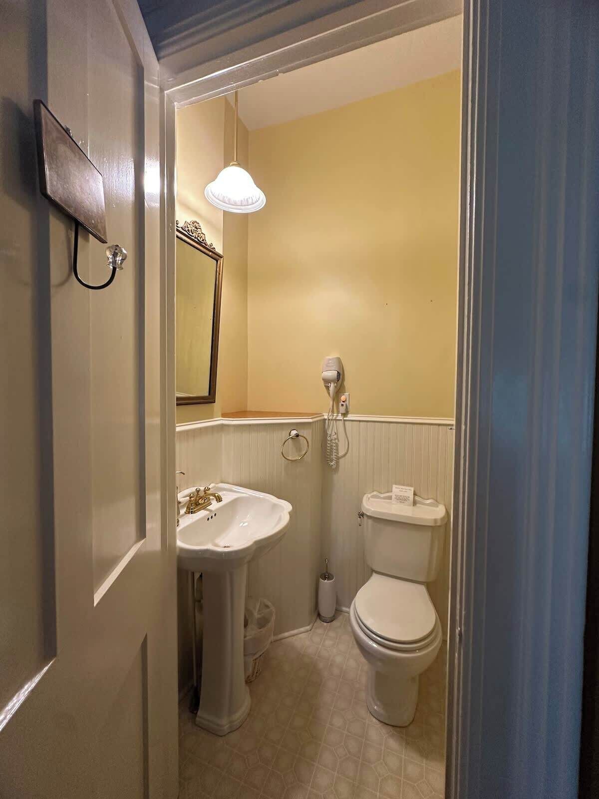 A bathroom with a sink, toilet, and a hairdryer on the wall.