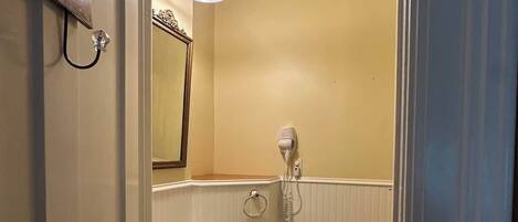 A bathroom with a sink, toilet, and a hairdryer on the wall.