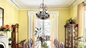 A dining room with a long table, chairs, a chandelier, and a fireplace. - Merriam Family Suite - The Belvedere Inn (Oswego)