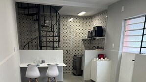 Cocina compacta con comedor, que incluye una escalera, microondas, refrigerador y un salpicadero con diseño.