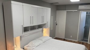 Un dormitorio con cama, armario, mesita de noche y espejo.