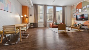 Un salon moderne comprenant un coin repas, de grandes fenêtres, un téléviseur à écran plat et une vue sur la ville.