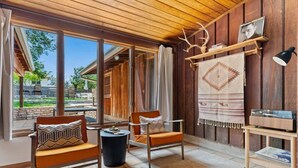 A cozy room with wooden walls and a large window, furnished with two chairs and a small table. - * Stunning FBG Retreat * | Sleeps 10 (Fredericksburg)