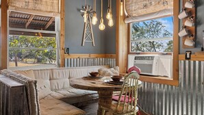 Un comedor acogedor con una mesa de madera, un banco acolchado y lámparas colgantes.