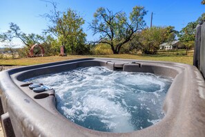 A hot tub with a clear view of the surrounding landscape, including trees and a distant house. - Unplug, Unwind, and Reconnect at Glowing Embers! (Fredericksburg)