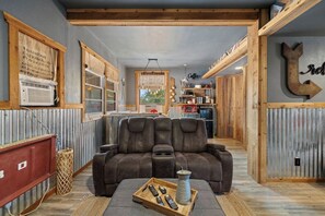Ein gemütliches Wohnzimmer mit einem Ledersofa, einem Couchtisch mit Fernbedienungen und einer rustikalen Einrichtung.