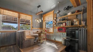 Una cocina rústica con un banco de madera, una mesa de comedor y un refrigerador.