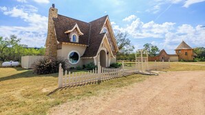 Une maison avec une façade en pierre, une fenêtre ronde et une clôture en piquets.