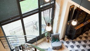 Un intérieur moderne avec un escalier, de grandes fenêtres et des luminaires suspendus.