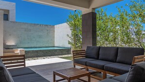 Ein Sitzbereich im Freien mit Pool, einem Holztisch und einer Couch.