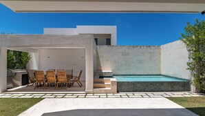 Eine moderne Außenpatio mit Pool, Grill und Holzstühlen.