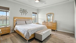 Un dormitorio con cama, cómoda, espejo y ventilador de techo.