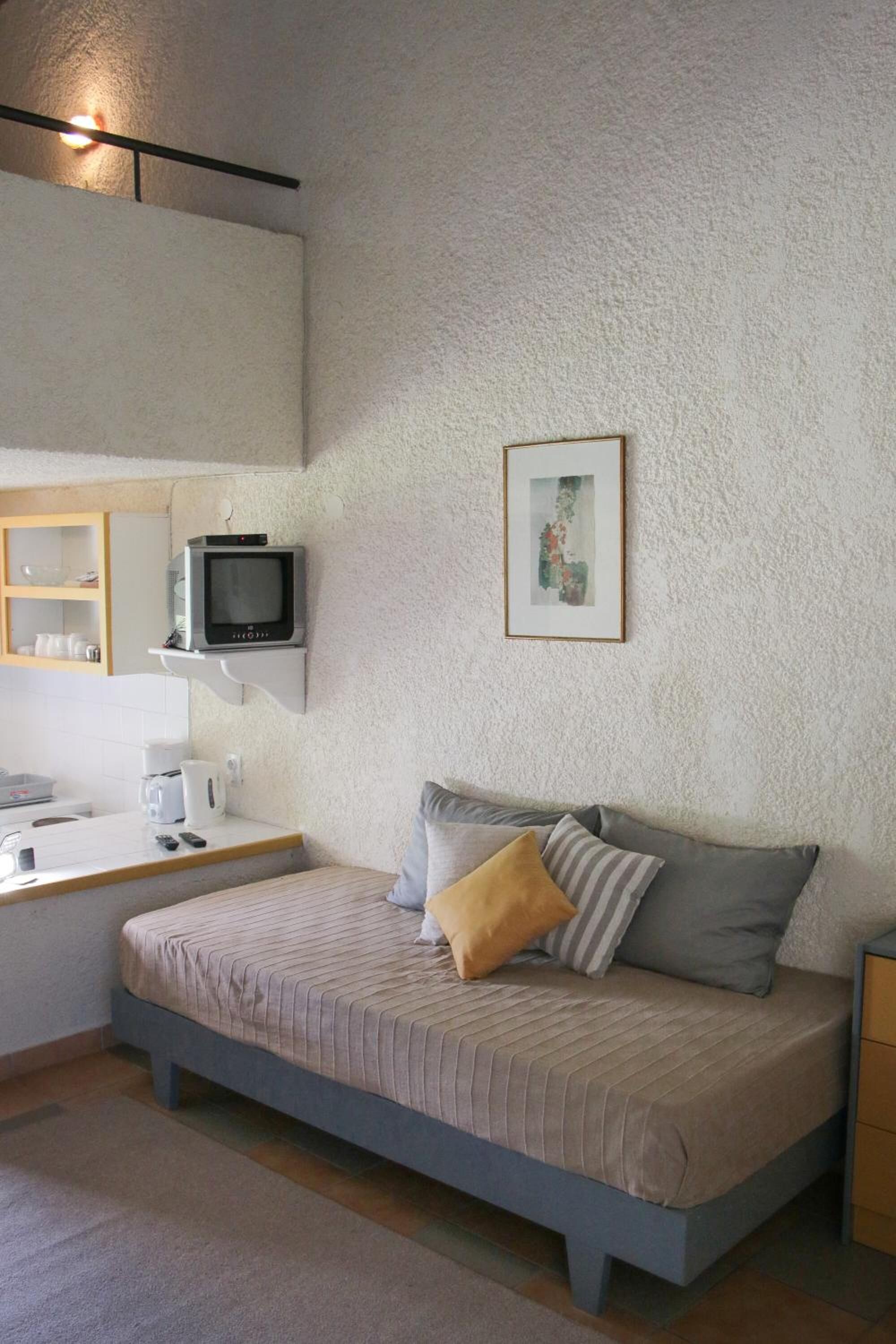 A bedroom with a bed, a television mounted on the wall, a small table, and a picture frame.