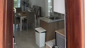 A compact kitchen with a sink, a small refrigerator, and a dining area with chairs and a table. - Beach Apartment in Stanza Mare Punta Cana (Punta Cana)