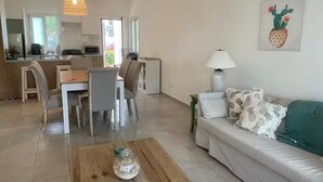 A modern living room with a sofa, coffee table, and dining area. - Beach Apartment in Stanza Mare Punta Cana (Punta Cana)