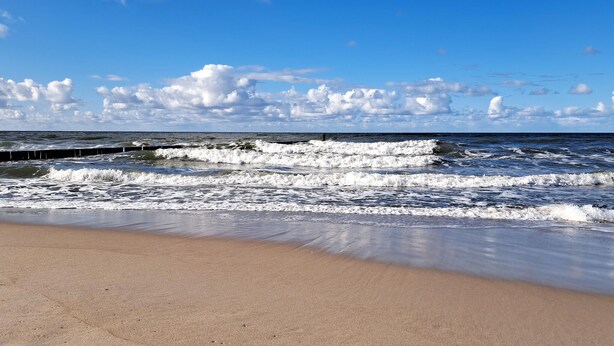 A beach with waves, a clear sky, and a wooden pier. - Gorgeous home in Osieki with house sea view (Osieki)