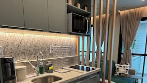A modern kitchen with grey cabinets, a stainless steel sink, and a built-in microwave.