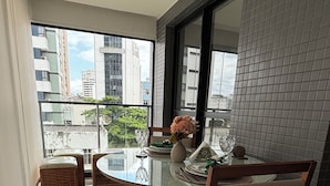 A modern dining area with a round glass table, wooden chairs, and a vase of flowers.