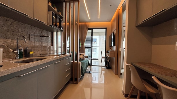 A modern kitchen with a built-in oven, a sink, and a dining area with a table and chairs.