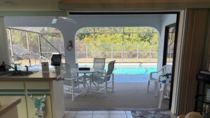 Una cocina con vista a una piscina, un comedor con sillas y una encimera con un lavamanos.