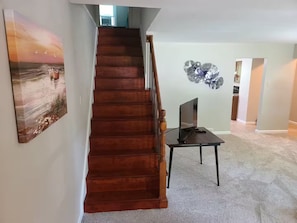 A wooden staircase leading to a landing with a flat-screen TV on a stand. - Sharon A - 8 Bed, Sleeps 11+ (Saint Charles)