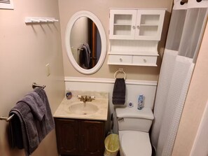Un baño con lavamanos, espejo, inodoro y armarios.
