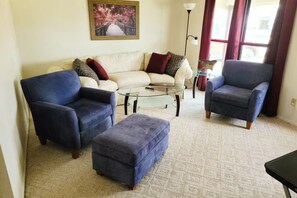 A living room with a sofa set, two armchairs, a coffee table, and a rug.