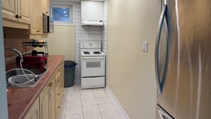 Una cocina compacta con armarios de madera, un refrigerador de acero inoxidable, una estufa blanca y una ventana sobre el lavamanos.