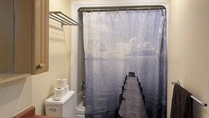 Un baño con cortina de ducha, toallero, inodoro y lavamanos.