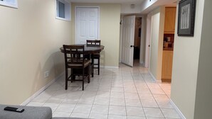 Comedor con una mesa y sillas, una puerta blanca y un pasillo que conduce a una zona de cocina.