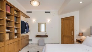 Et hotelværelse med seng, træskab, sminkebord og et spejl.