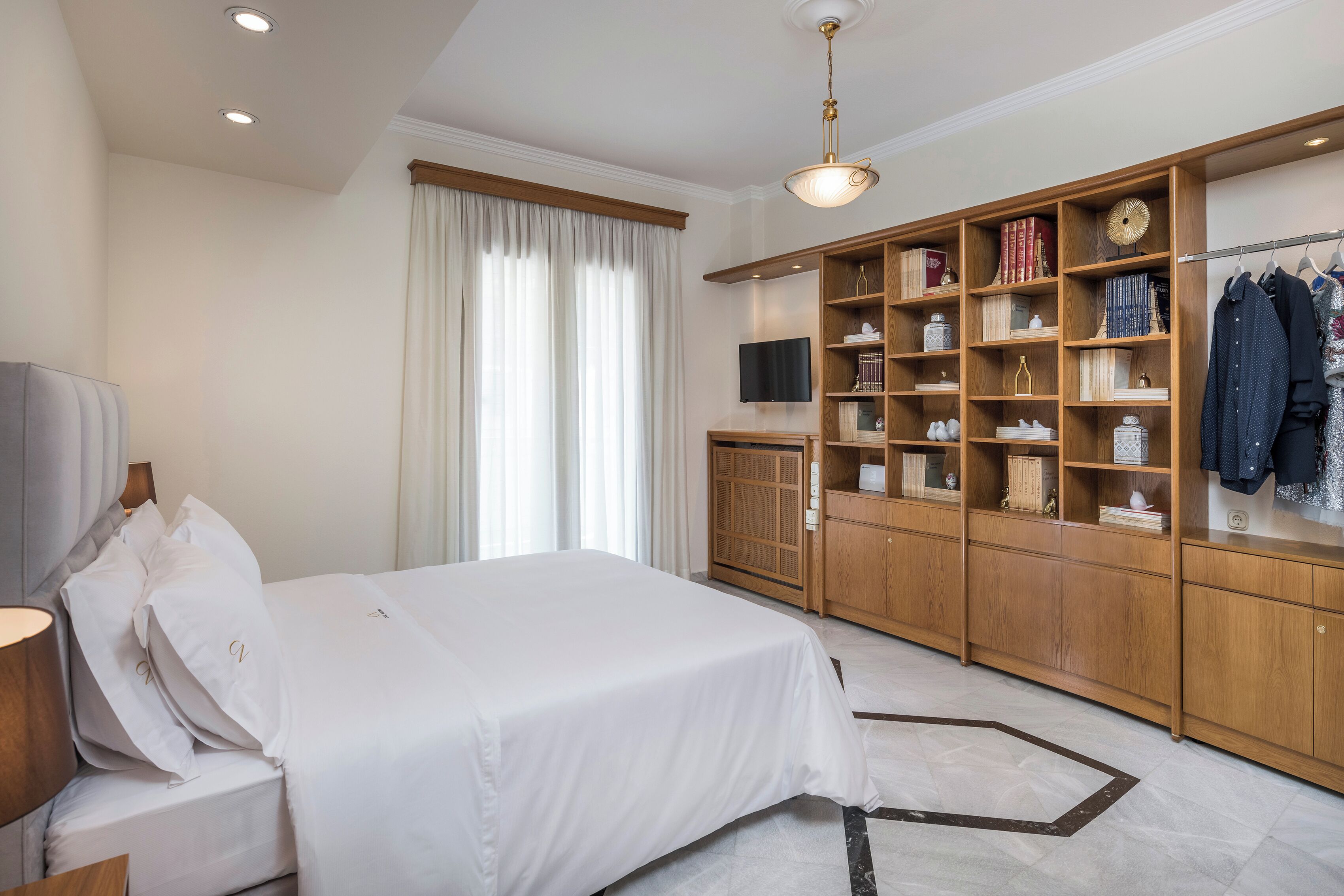 Una habitación de hotel con cama, televisión, armario y estantería.